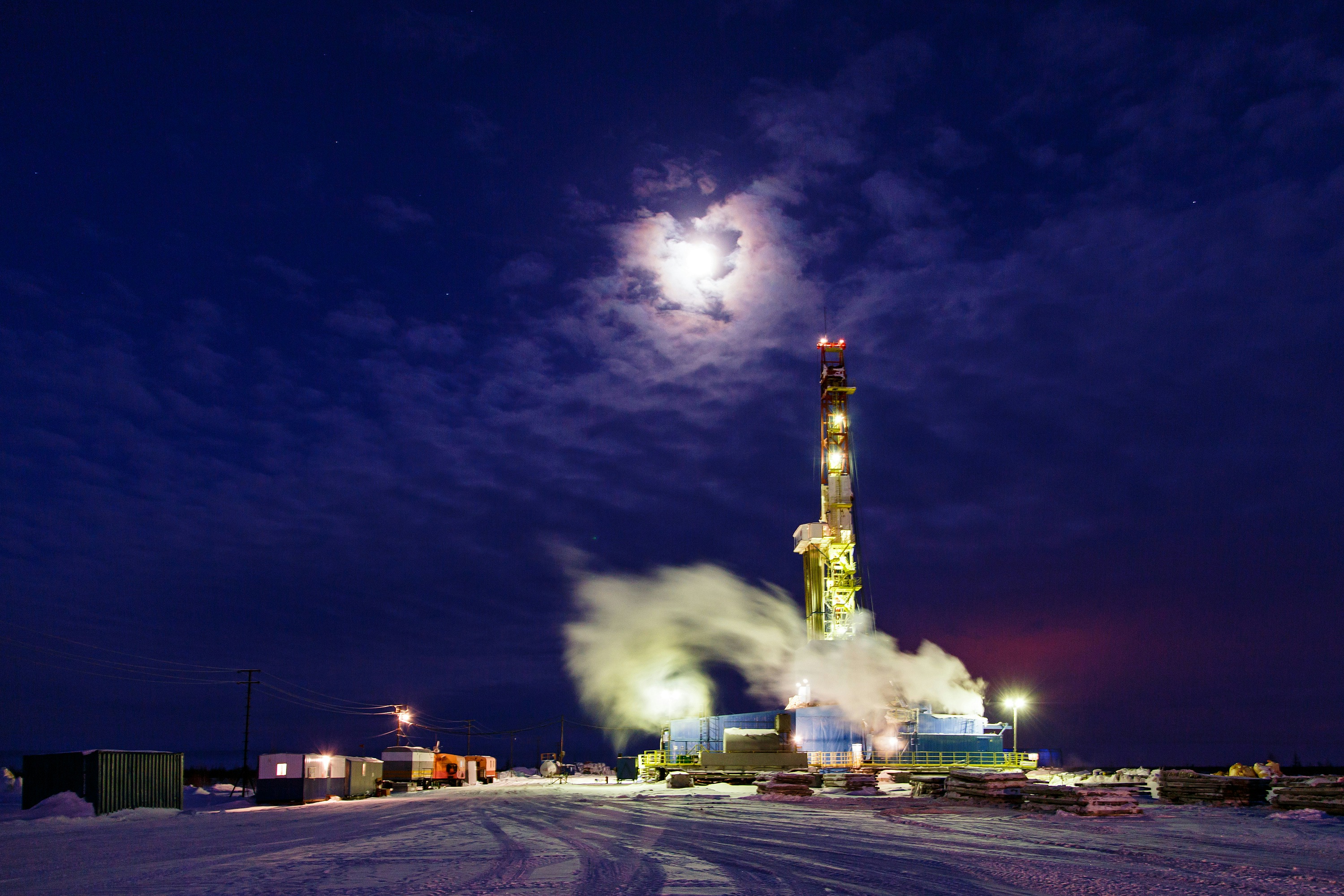 A land drilling rig illuminated beneath moonlit clouds, photographed by WORKSITE Ltd.